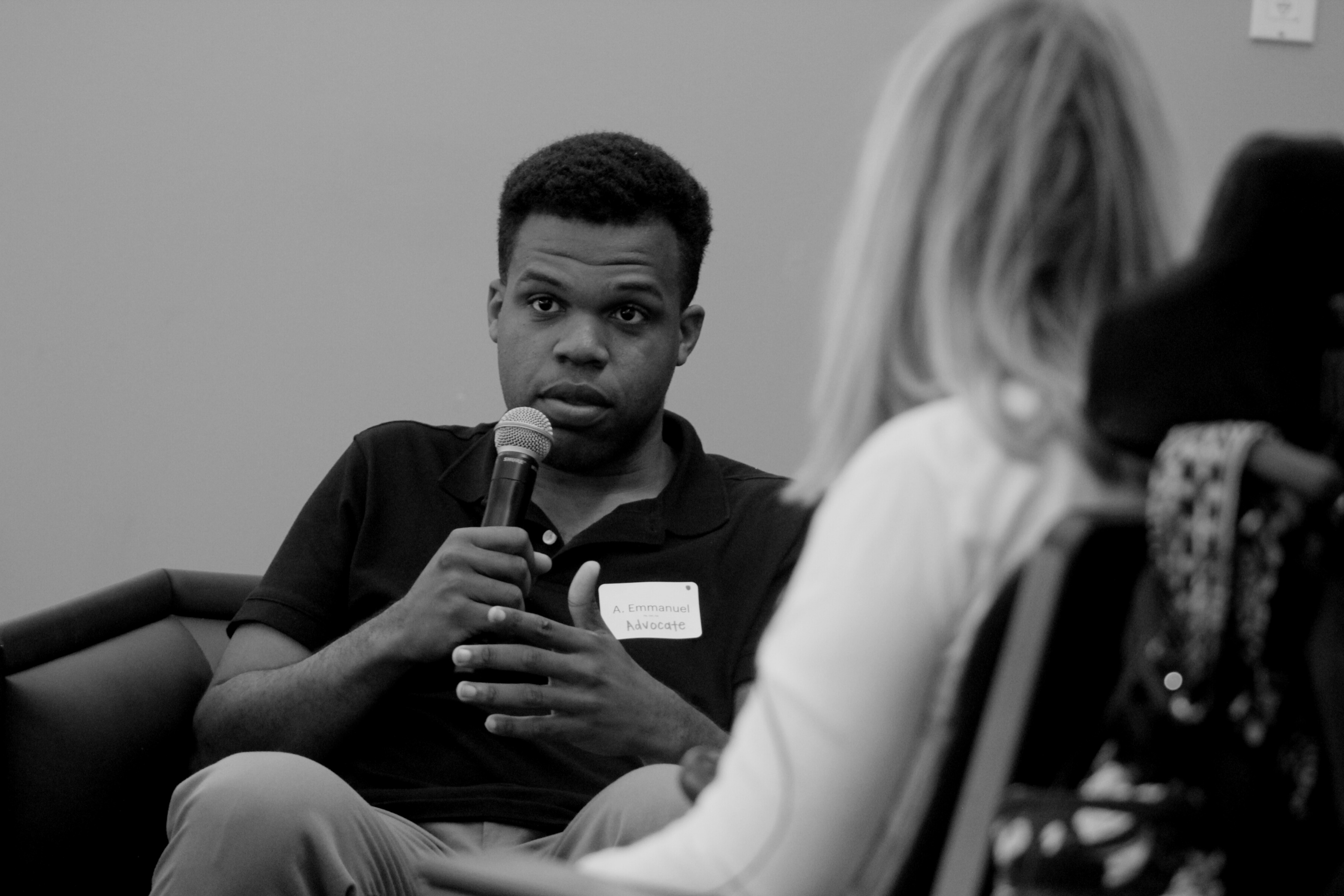 A black autistic man speaking into the microphone during a disability self-advocacy panel at an Illimitable workshop.