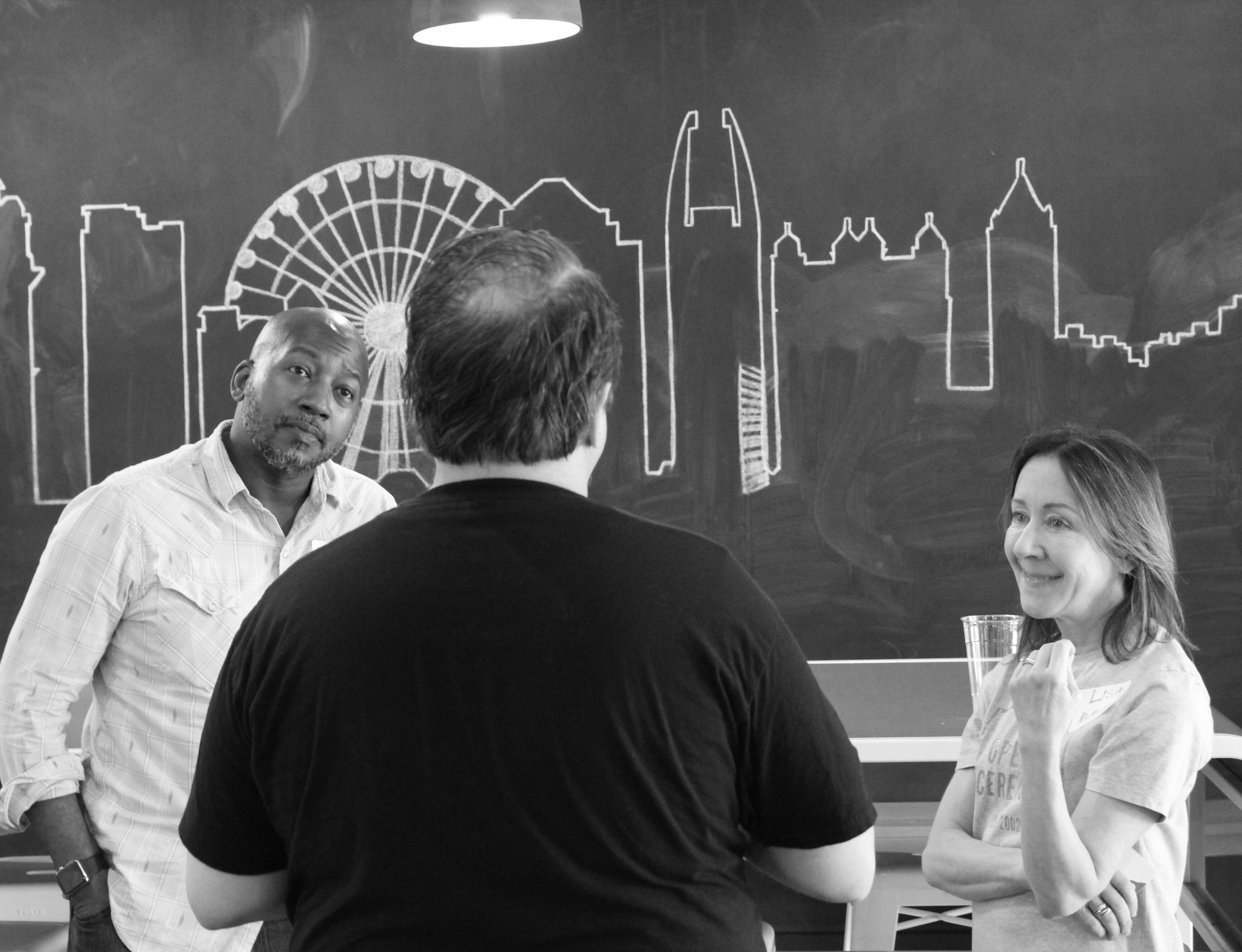 Diverse group smiling and networking with a drawing of buildings on a chalkboard in the background