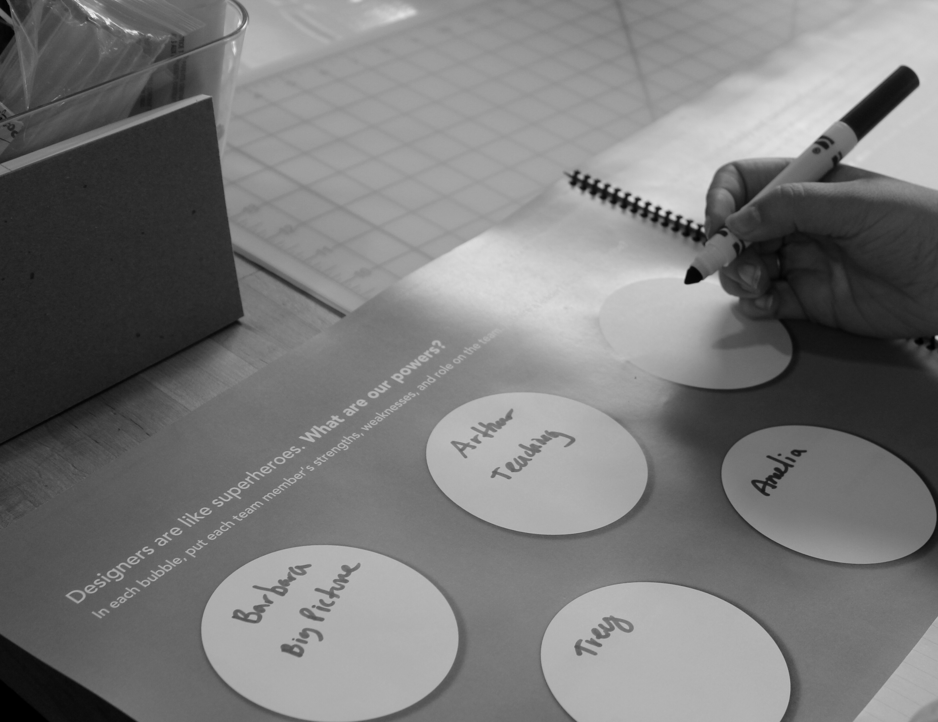 A woman writing her name in a partially completed design thinking booklet from an Illimitable workshop